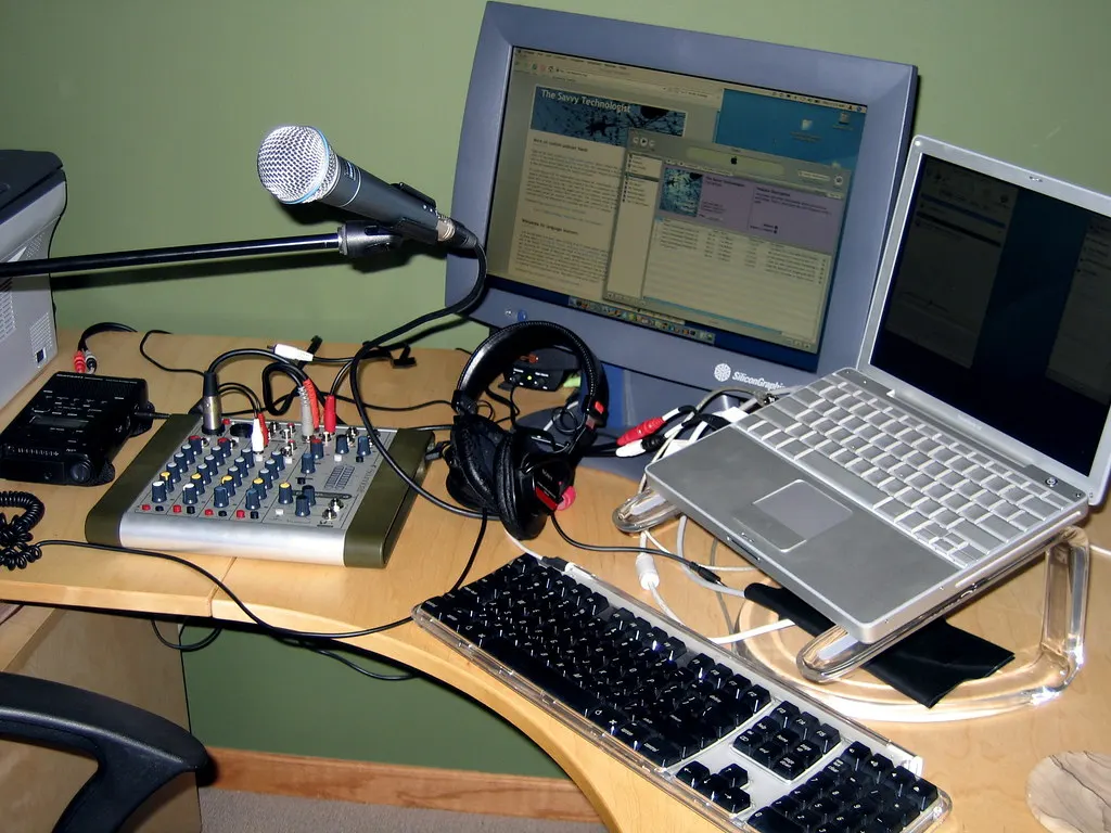 Podcastmicrofoon en koptelefoon op een bureau thuis, naast een laptop