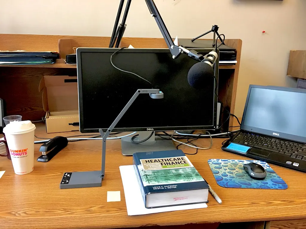 Videocamera gericht op twee mensen die aan de podcasttafel met elkaar in gesprek zijn
