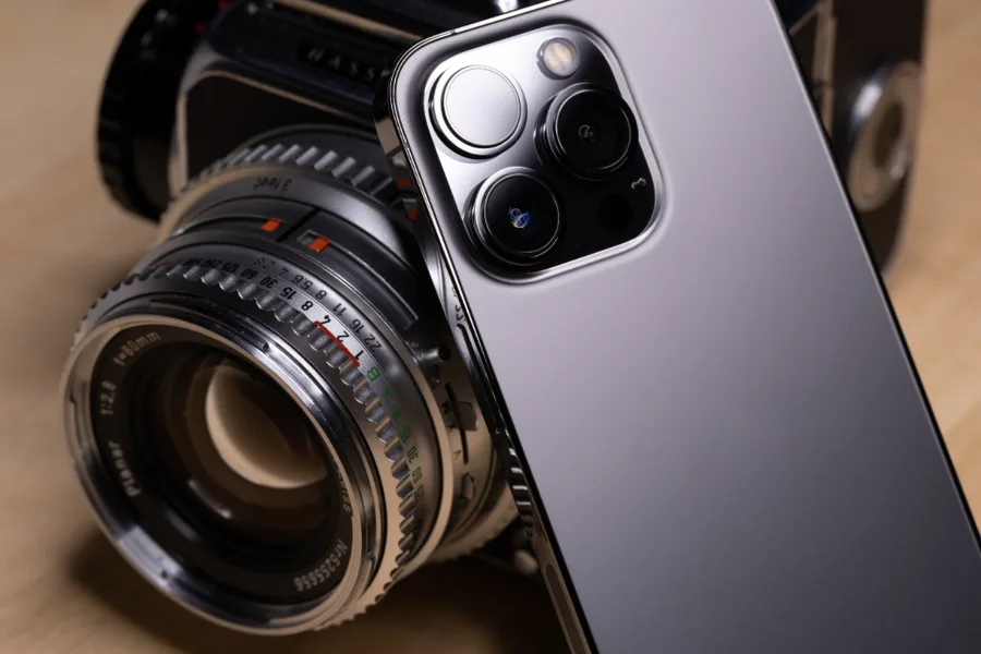 Klassieke fotocamera naast een moderne smartphone