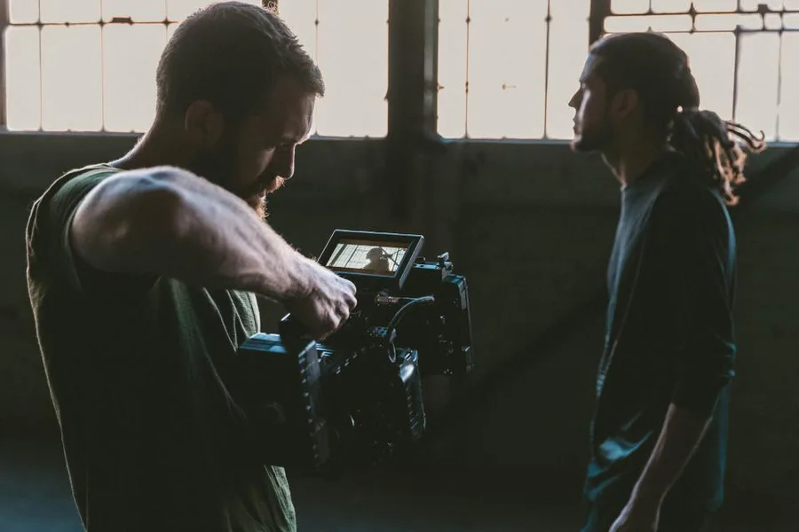 Twee makers achter een cinemacamera in een industriële ruimte