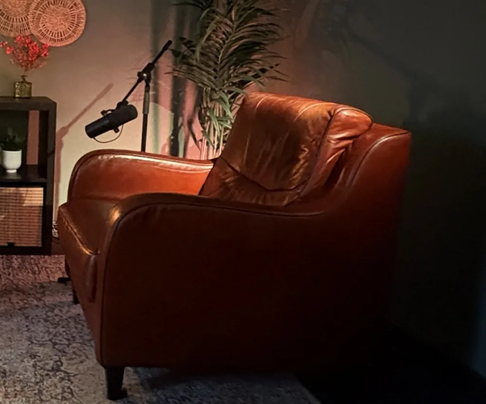 Een Shure-microfoon aan een statief boven een leren fauteuil in Podcaststudio Breda